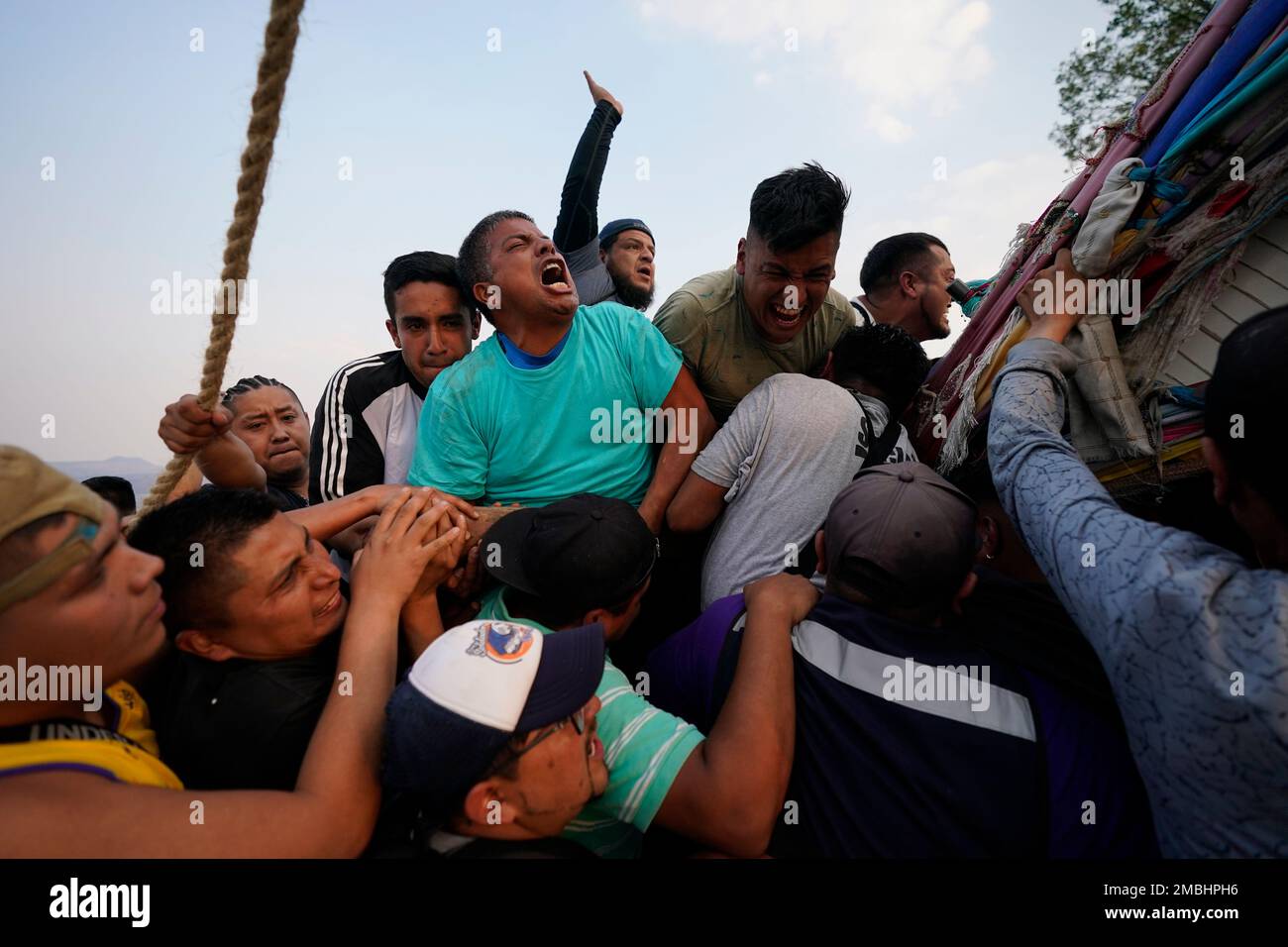 People work to lower a heavy, wooden cross from a hilltop to carry it to a church as part of celebrations marking the day of the Holy Cross, in the Santa Cruz Xochitpec neighborhood of Mexico City, late Monday, May 2, 2022. The importance of the fabric-draped cross is reflected in the town's very name, which means "Holy Cross of the Flowered Hill." (AP Photo/Eduardo Verdugo) Banque D'Images