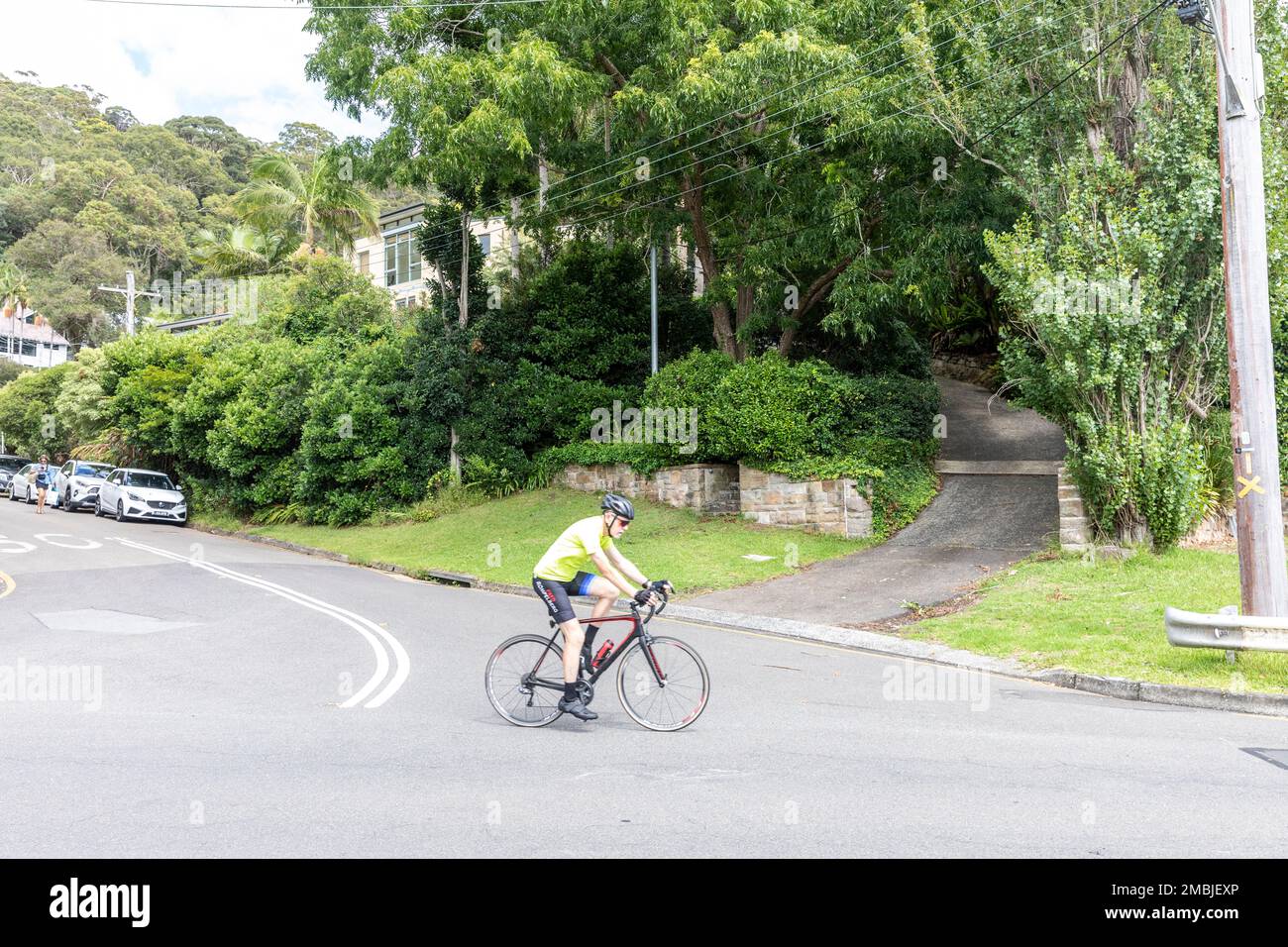Un ancien homme à la retraite, qui fait du vélo, roule dans les rues de Church point à côté de Pittwater, Sydney, Nouvelle-Galles du Sud, Australie Banque D'Images
