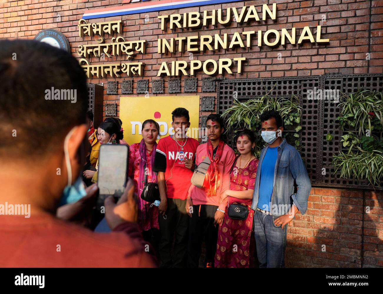 A Nepalese migrant worker takes photos with his family member before taking a flight out to Qatar at Tribhuvan International airport in Kathmandu, Nepal, Friday, April 15, 2022. Nepal is running low on foreign currency reserve that is needed to import everything from cars, all the oil products and medical equipment and it will last only for the next seven months, a central bank official said Friday. (AP Photo/Niranjan Shrestha) Banque D'Images