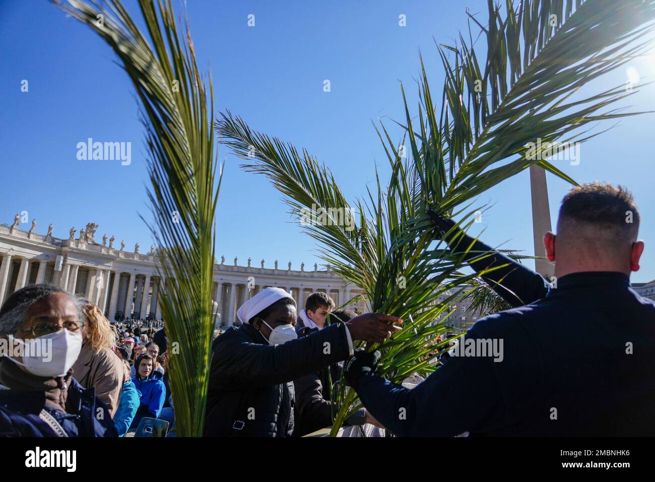 Palm tree branches are distributed to people as they wait for the arrival of Pope Francis to celebrate Palm Sunday Mass in St. Peter's Square at the Vatican, Sunday, April 10, 2022. The Roman Catholic Church enters Holy Week, retracing the story of the crucifixion of Jesus and his resurrection three days later on Easter Sunday. (AP Photo/Greorio Borgia) Banque D'Images
