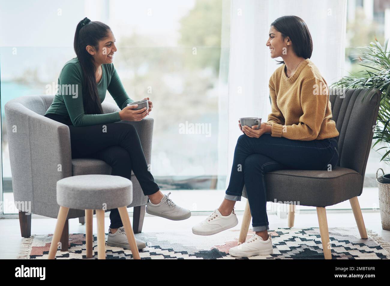 Passer du temps avec ma sœur est la seule thérapie dont j'ai besoin. deux jeunes femmes buvant du café tout en étant assises à la maison. Banque D'Images
