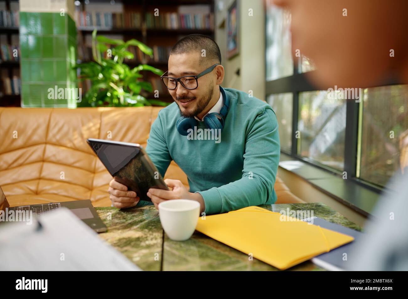 Jeune employé souriant utilisant l'écran de tablette numérique espace de travail des collègues Banque D'Images