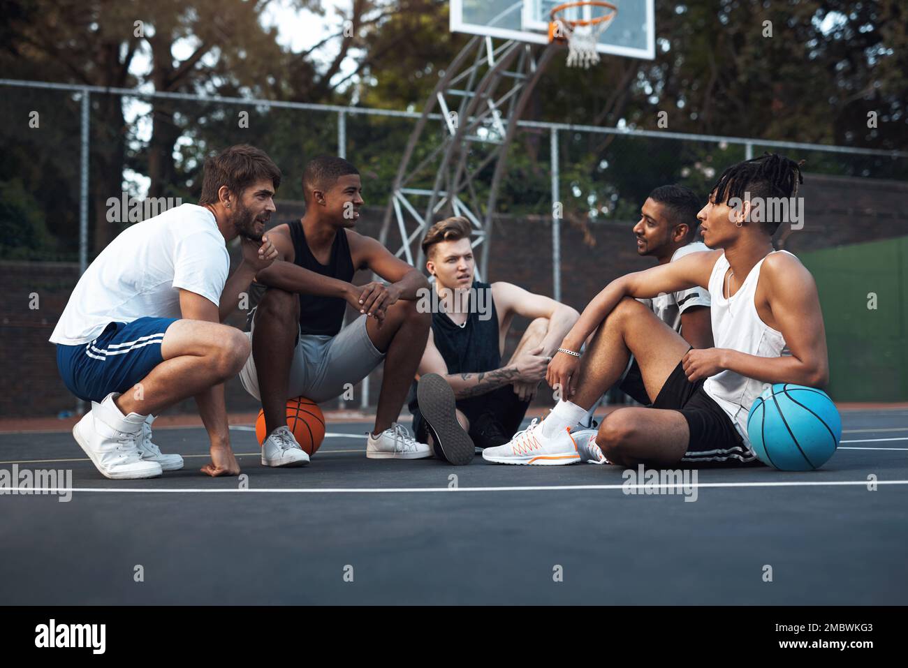 Parler d'une chose qu'ils aiment tous - le basket-ball. un groupe de jeunes hommes sportifs qui traînaient sur un terrain de basket-ball. Banque D'Images