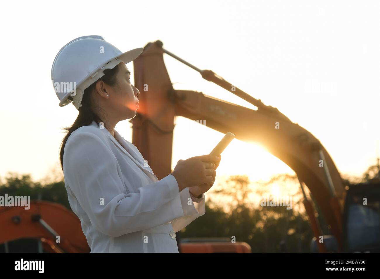 Portrait d'un ingénieur asiatique portant un casque blanc utilisant un smartphone sur un lieu de travail. Ingénieur civil vérifiant après les travaux sur le chantier pendant Banque D'Images