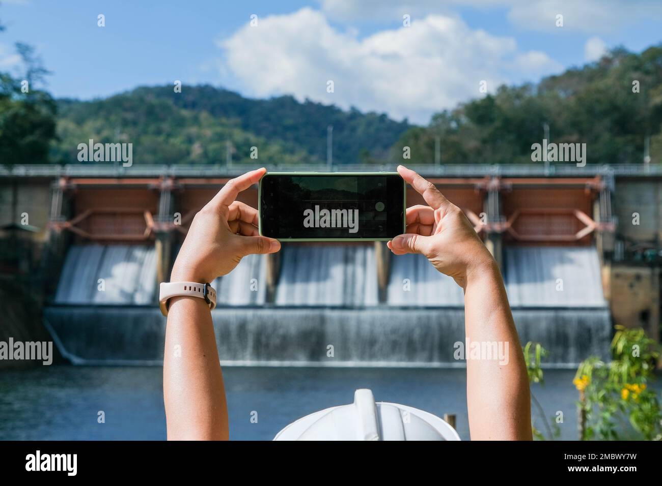 Les ingénieurs de l'environnement utilisent des téléphones mobiles pour prendre des photos et enregistrer des données analysant les contaminants de l'eau des barrages. Concept de l'eau et de l'écologie. Banque D'Images