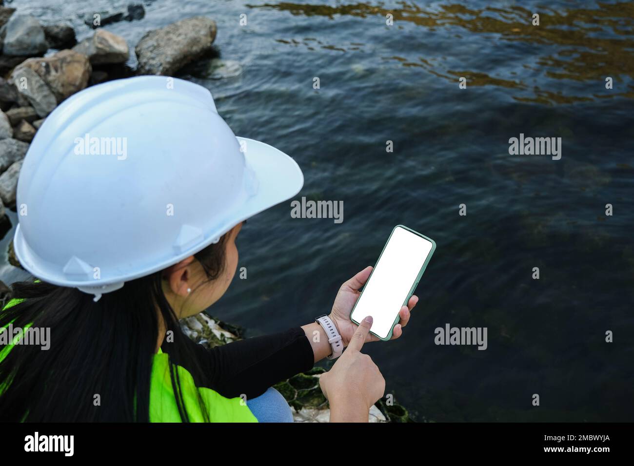 L'ingénieur en environnement utilise un téléphone portable pour enregistrer les données d'analyse de l'eau dans le barrage. Les écologistes collectent des échantillons d'eau du barrage pour vérifier la présence de con Banque D'Images