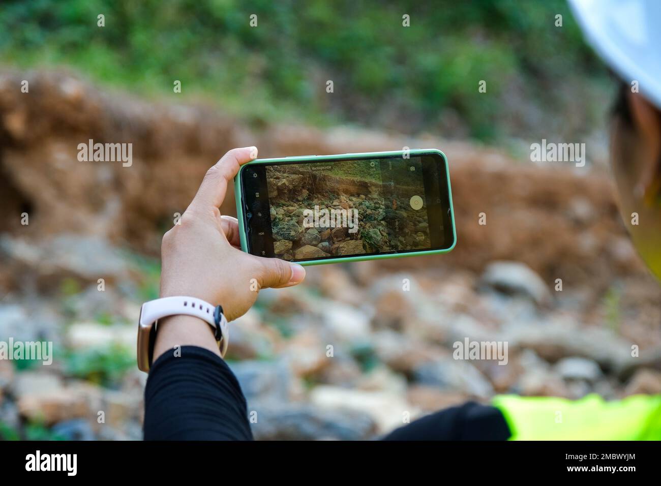 Une géologue féminine utilisant un téléphone portable pour prendre des photos, examiner la nature et analyser des rochers ou des cailloux. Les chercheurs recueillent des échantillons de matériel biologique Banque D'Images