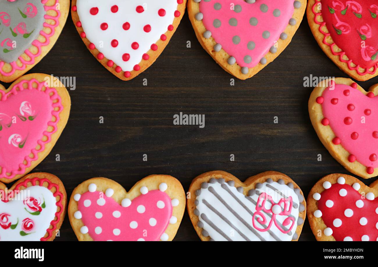 Magnifiques cadres en forme de coeur avec de jolis biscuits à motifs sur fond noir Banque D'Images