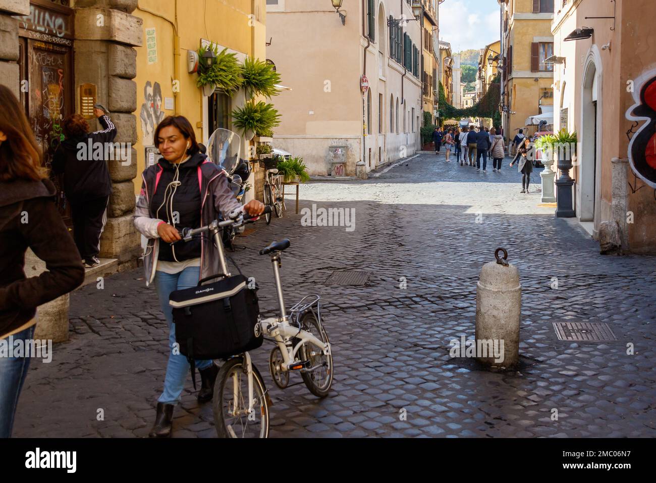 Une jeune femme marche à vélo dans une rue du Trastevere, à Rome. Banque D'Images