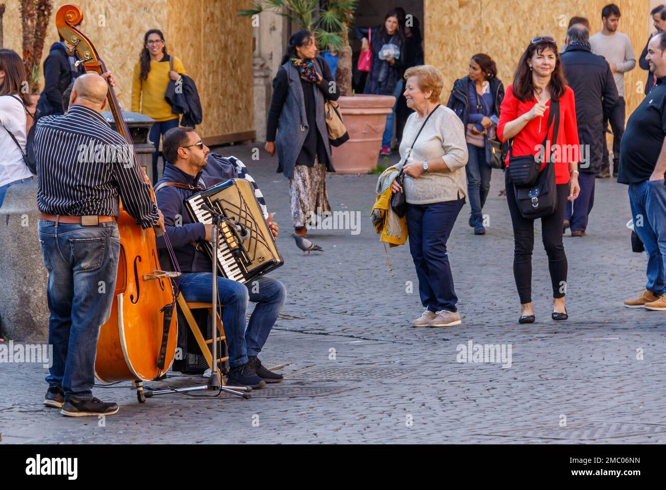 Une vieille femme danse avec la musique d'un groupe de rue sur la Piazza di Santa Maria, Rome. Banque D'Images