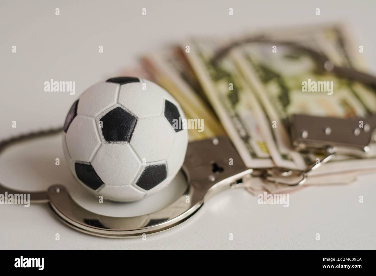Ballon de football avec argent et menottes. Corruption dans le football, les jeux d'argent et la corruption dans le sport. Banque D'Images