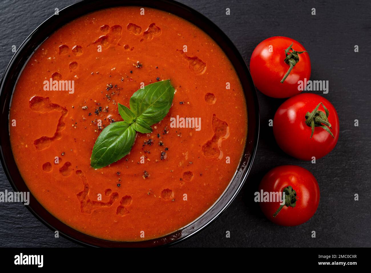 Purée de tomate dans un bol noir. Plat de légumes chaud fraîchement préparé, composé de tomates en purée, d'ail et de basilic. Cuisine méditerranéenne. Plat végétalien. Banque D'Images