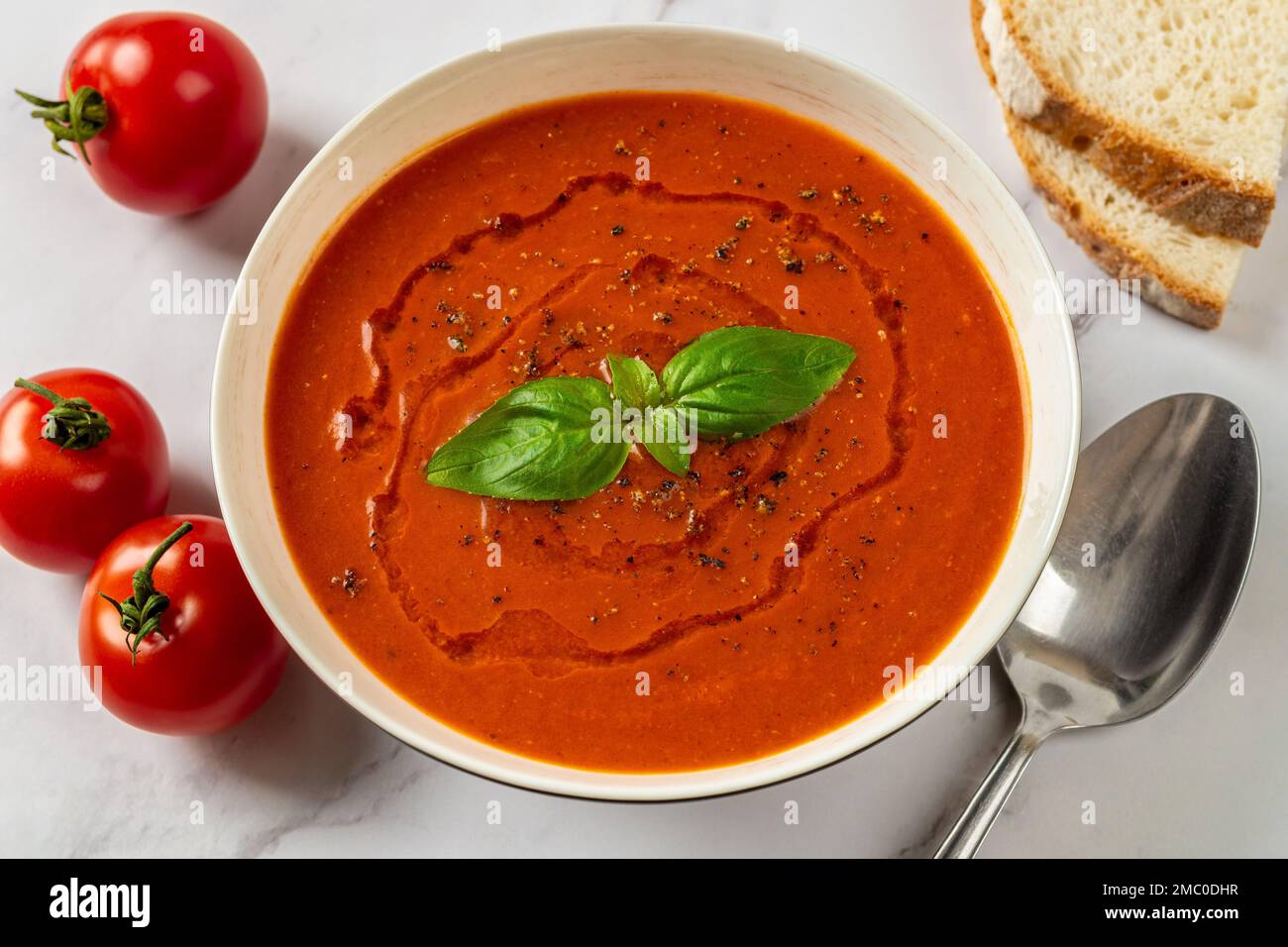 Soupe de tomates chaudes dans un bol blanc en gros plan. Plat de légumes frais de tomates en purée, ail et basilic prêts à manger. Plat végétarien sain. Banque D'Images