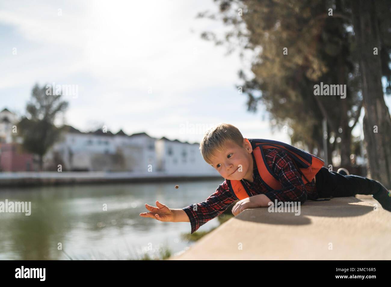 Mignon petit garçon jouant avec une petite balle au bord de la rivière à Tavira, Portugal Banque D'Images