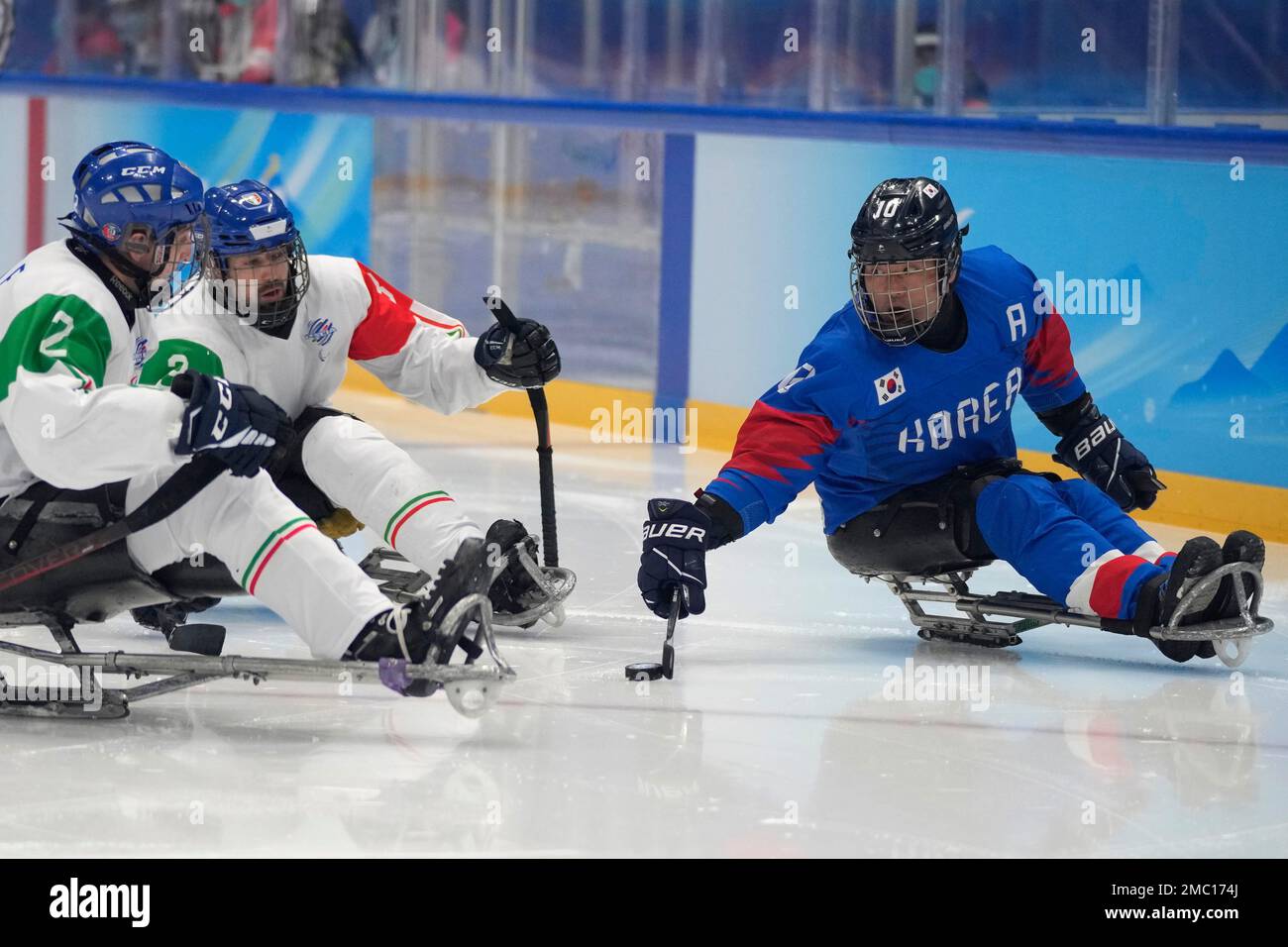 South Korea's Cho Young-jae, right, battles for the puck against Italy's Alex Enderle, left, and Gianluigi Rosa during their para ice hockey qualifying final match at the 2022 Winter Paralympics, Wednesday, March 9, 2022, in Beijing. (AP Photo/Dita Alangkara) Banque D'Images