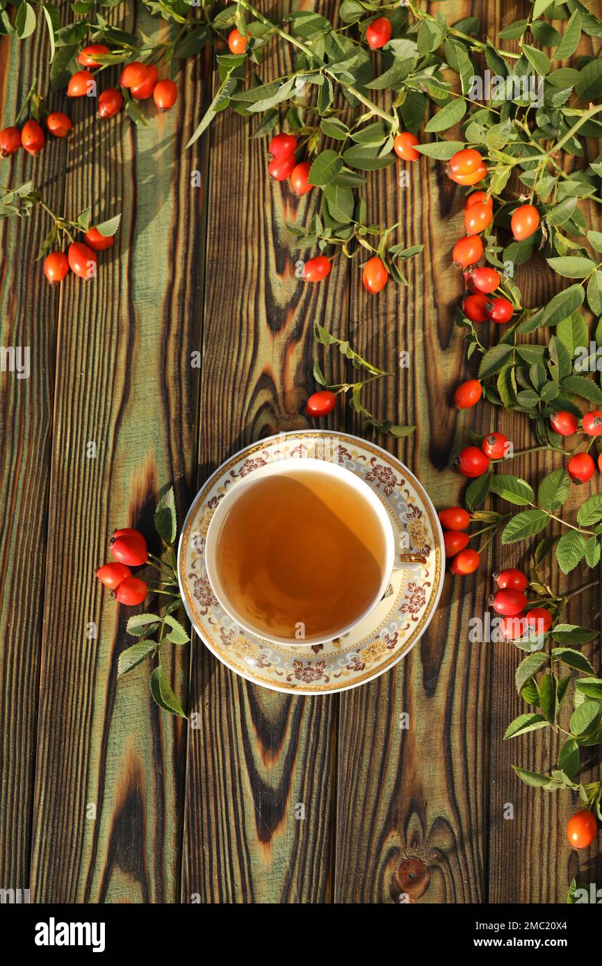 Tasse de thé avec baies de rose sur fond de bois Banque D'Images