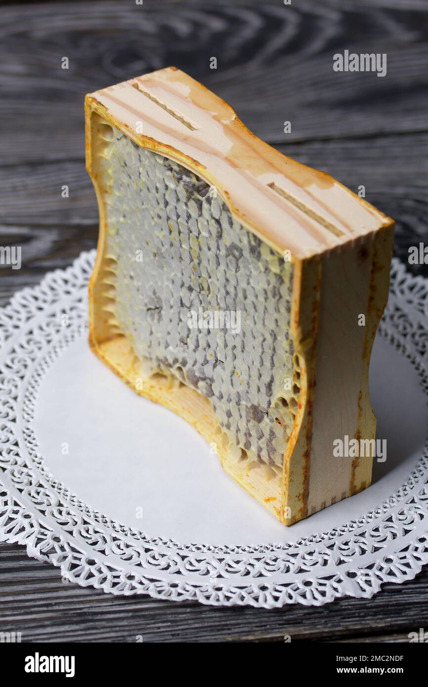 Miel en nid d'abeille dans un cadre en bois. Sur les planches de pin noir. Sur fond noir. Gros plan. Banque D'Images