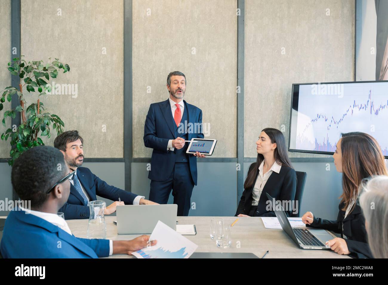 Leader caucasien avec une tablette à la main pour coacher les gens d'affaires intéressés, en offrant une présentation d'atelier pédagogique à l'écoute des employés concentrés Banque D'Images