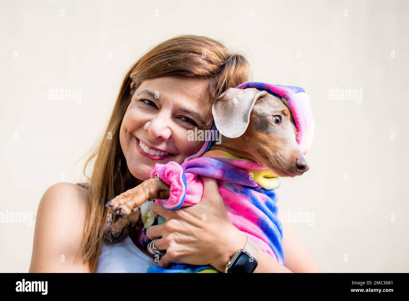 Femme latine tenant son chien vêtu de la même façon. Elle regarde la caméra. Banque D'Images