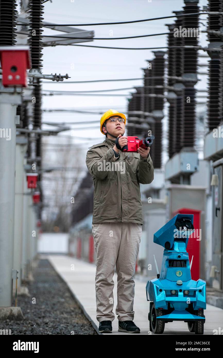TAIZHOU, CHINE - 21 JANVIER 2023 - Un membre du personnel en service inspecte le fonctionnement de l'équipement de sous-station avec un robot d'inspection intelligent au Banque D'Images