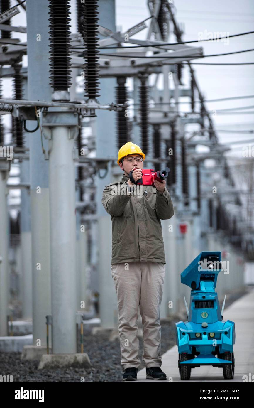 TAIZHOU, CHINE - 21 JANVIER 2023 - Un membre du personnel en service inspecte le fonctionnement de l'équipement de sous-station avec un robot d'inspection intelligent au Banque D'Images