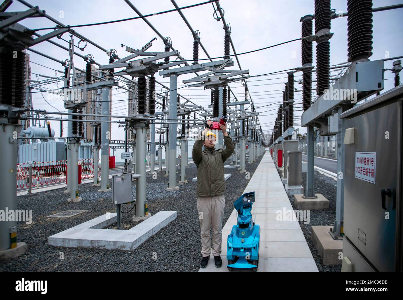 TAIZHOU, CHINE - 21 JANVIER 2023 - Un membre du personnel en service inspecte le fonctionnement de l'équipement de sous-station avec un robot d'inspection intelligent au Banque D'Images