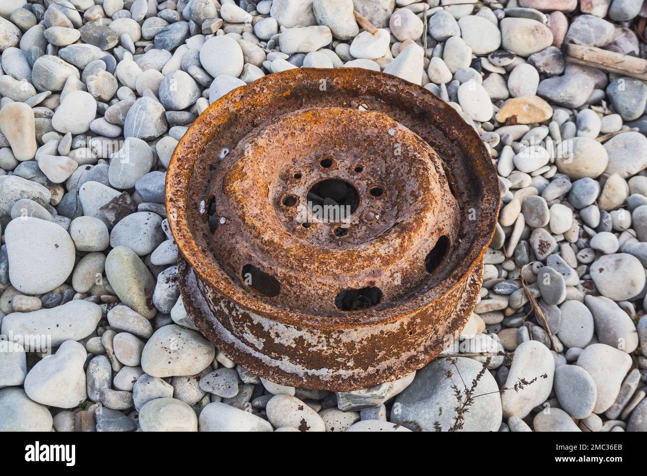 Ancienne roue de voiture, jante en alliage rouillé de voiture sur des pierres au bord de la rivière Banque D'Images