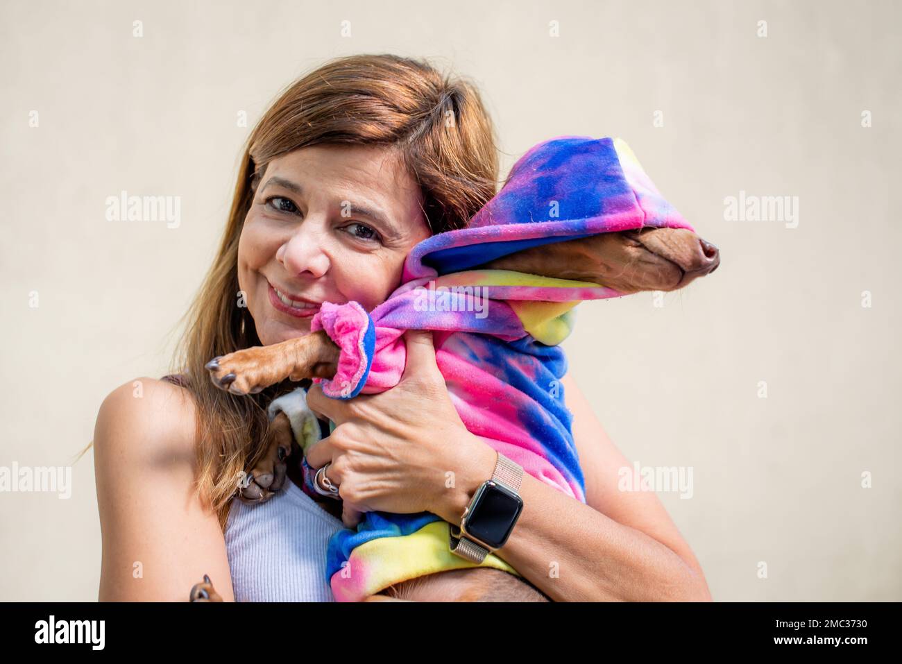 Femme latine tenant son chien vêtu de la même façon. Elle regarde la caméra. Banque D'Images