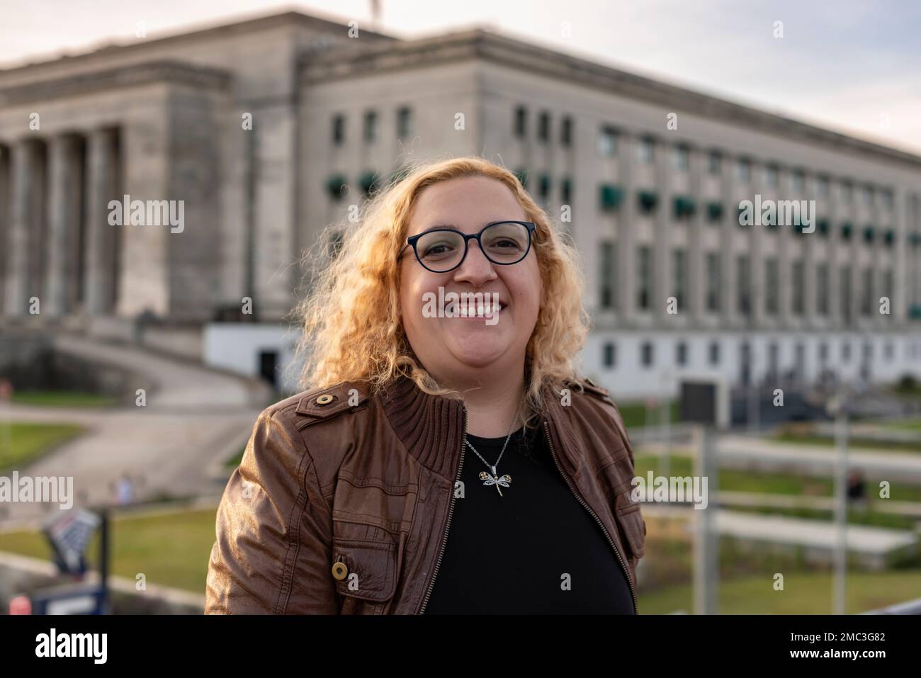 Portrait d'une femme blonde et courbeuse de plus taille regardant l'appareil photo tout en souriant dans un fond universitaire Banque D'Images