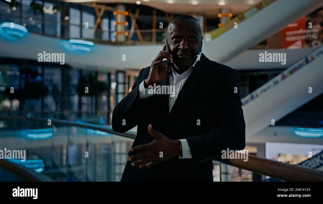 50s conseiller homme téléphone appeler collègues partenaire d'affaires parler avec le smartphone à l'intérieur dans la société de bureau indiquant les directives expliquant. Africain Banque D'Images