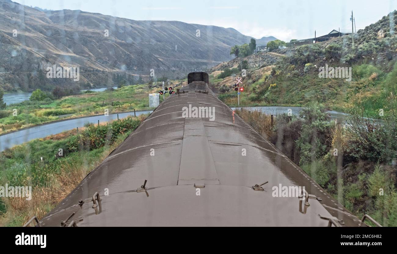 En regardant par la pluie striée deuxième fenêtre d'étage d'un train de tour les montagnes de l'ouest du Canada avec un ciel gris en arrière-plan Banque D'Images