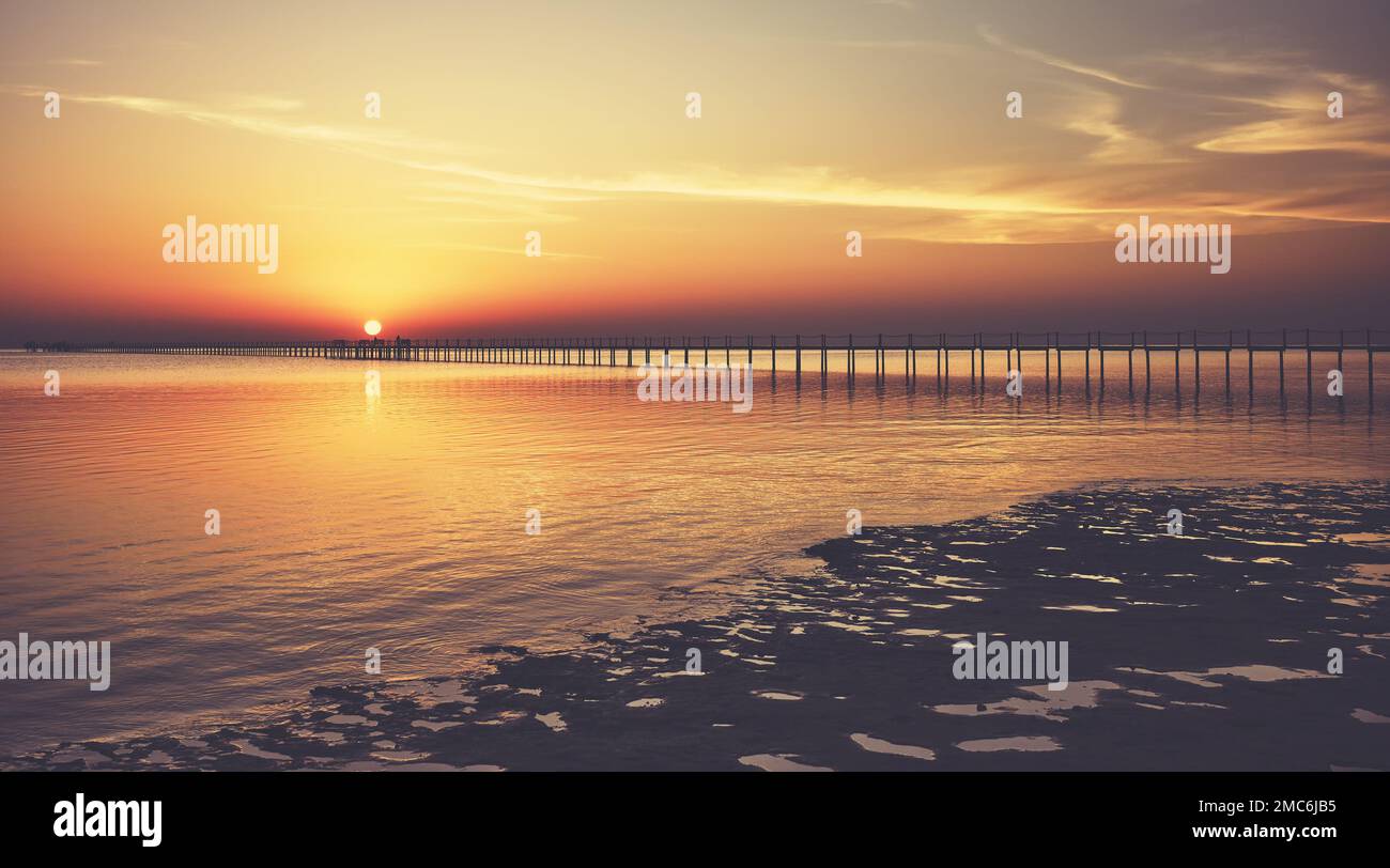 Vue sur la mer avec une silhouette de jetée en bois au coucher du soleil, tons de couleur appliqués. Banque D'Images