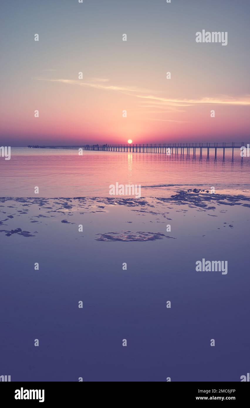 Vue sur la mer avec une silhouette de jetée en bois au coucher du soleil, tons de couleur appliqués. Banque D'Images