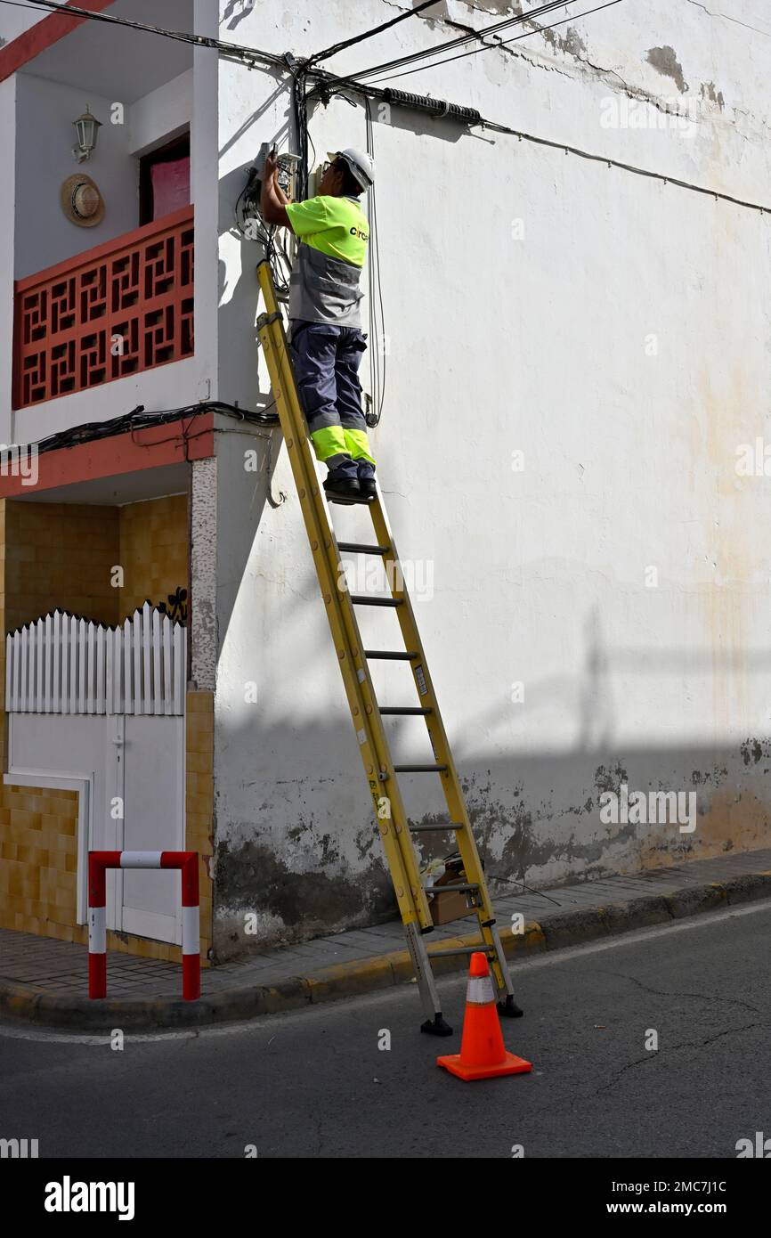 Ingénieur travaillant en haut de l'échelle en installant un câble à fibre optique Banque D'Images