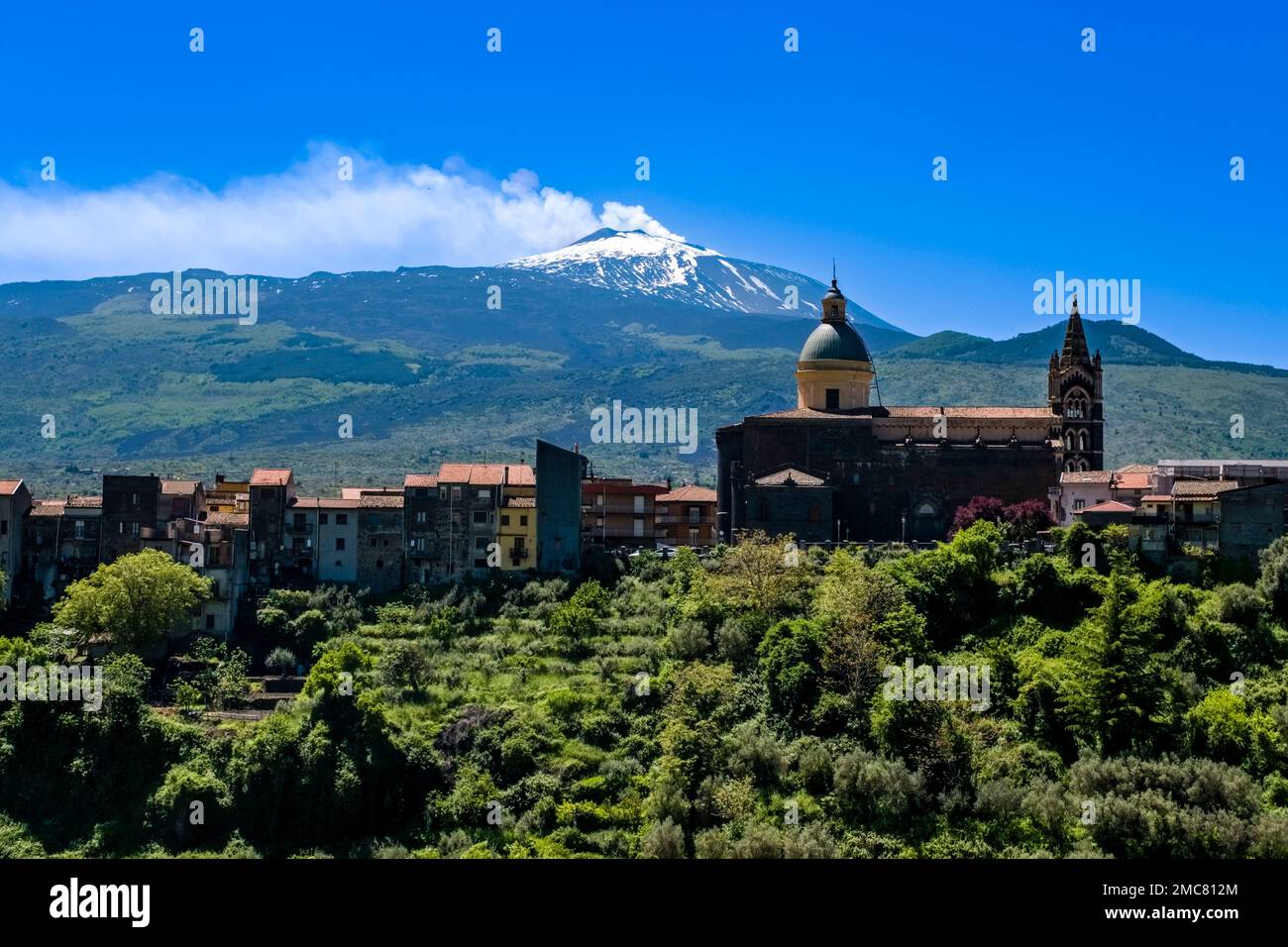 Vue sur l'église basilique de Santa Maria Assunta et les maisons de la ville de Randazzo, les pentes vertes et le sommet du volcan Etna, Mongibel Banque D'Images