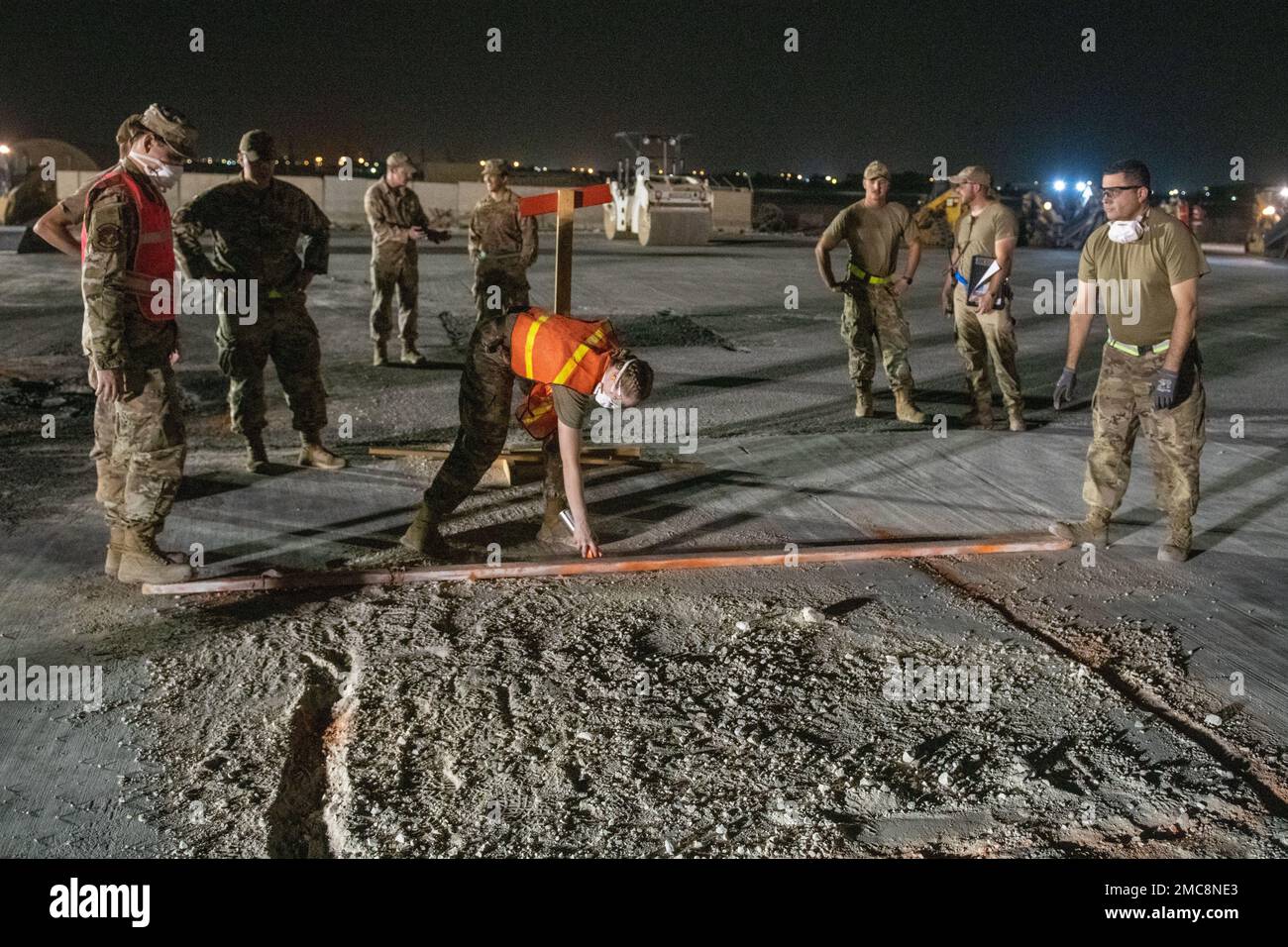 ÉTATS-UNIS Les assistants du génie de la Force aérienne de l'escadron 379th du génie civil expéditionnaire pulvérisent des lignes orange sur le trottoir entourant un cratère lors d'un exercice de réparation de ligne de vol sur la base aérienne Al Udeid, Qatar, 27 juin 2022. Le cratère est extrait à l'aide de machines lourdes, puis remplacé. Banque D'Images