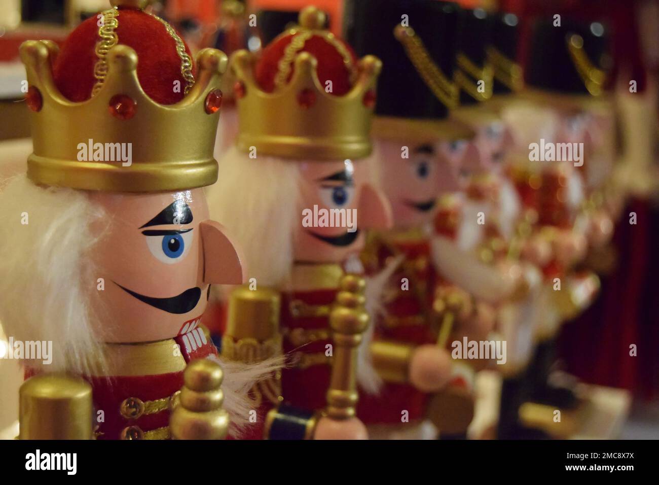 Une rangée de décorations de Noël traditionnelles en bois rouge et or portant une combinaison de couronnes et de chapeaux soldats. Banque D'Images