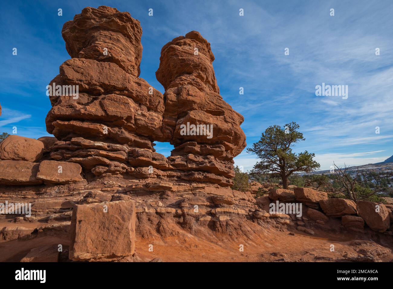 Deux pinacles de grès rouge avec une fenêtre naturelle érodée dans leur centre dans un emplacement naturel entouré par un beau ciel bleu clair Banque D'Images