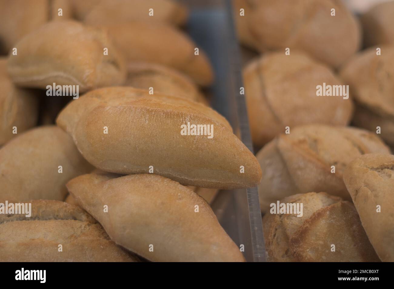 Un présentoir rempli de petits pains. Un magasin avec des petits pains délicieux, croustillants et frais à l'intérieur. Petits pains fraîchement cuits dans une boulangerie. Artisanat de boulangerie Banque D'Images