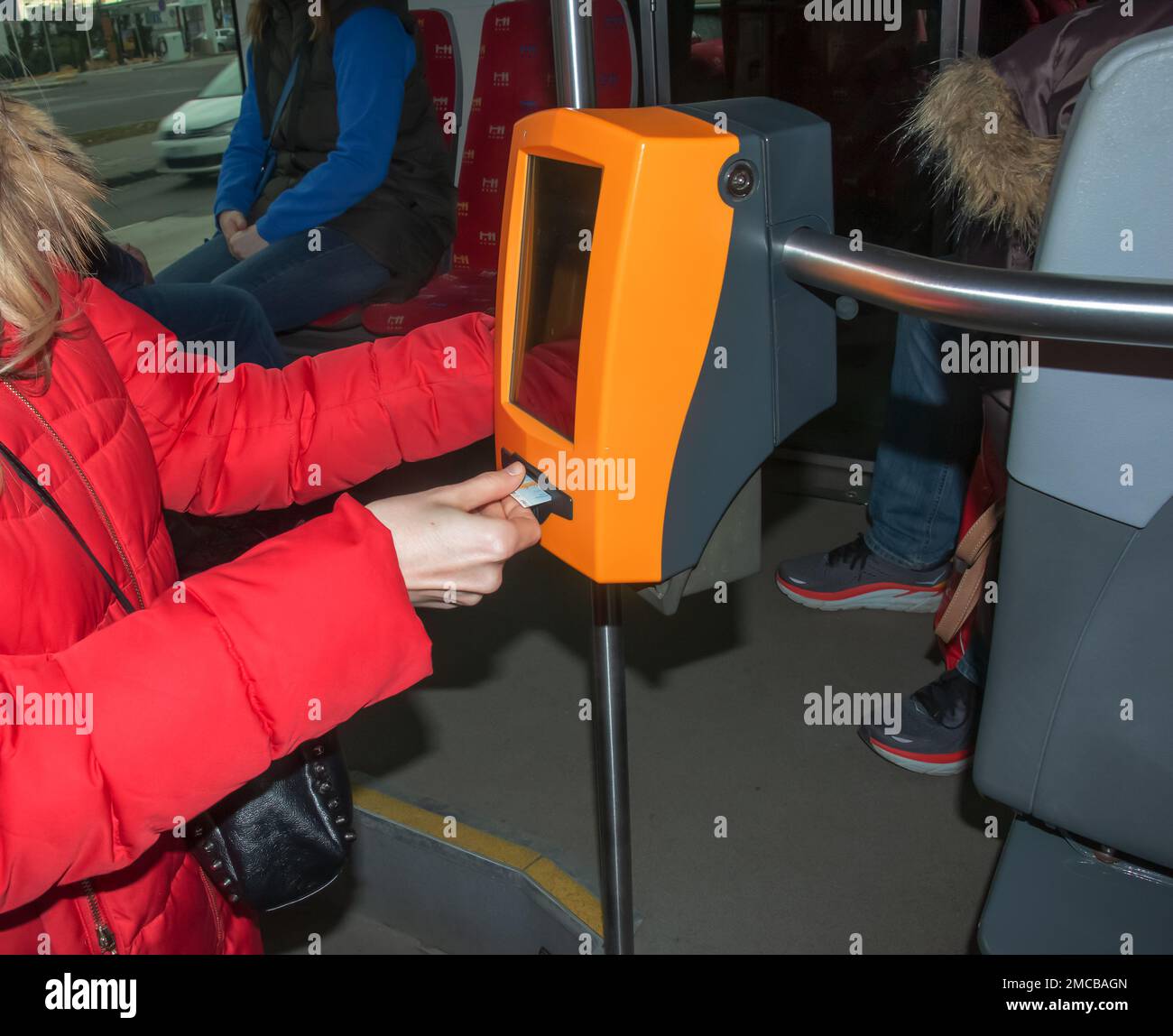 Jeune femme élégante utilisant une machine à perforer les tickets dans les transports en commun. La fille frappe le billet. Banque D'Images