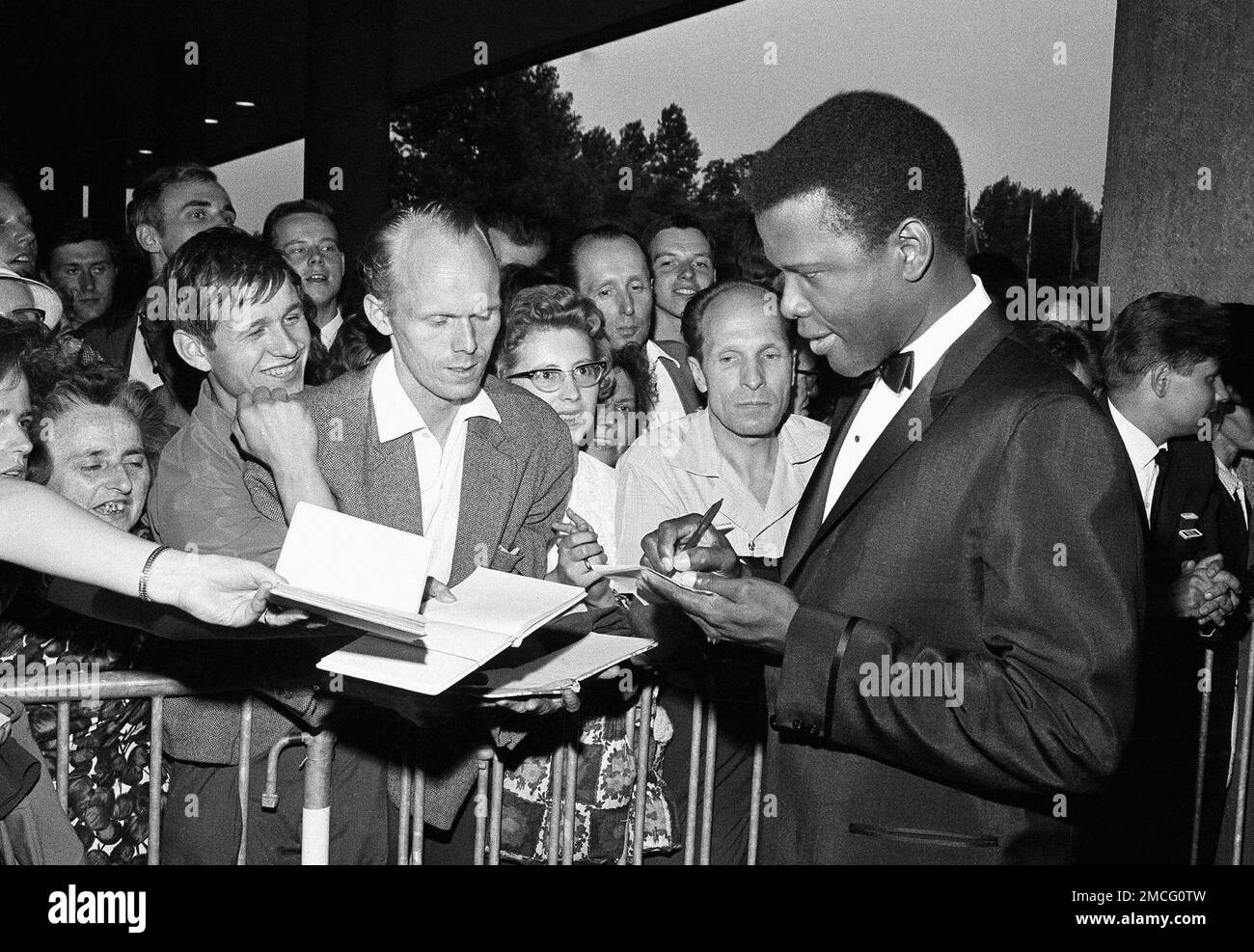 REMOVES REFERENCE TO THE BAHAMAS -FILE - Sidney Poitier signs autographs before the opening of the 14th International Film Festival at the West Berlin congress hall on June 26, 1964 in Berlin. Poitier, the groundbreaking actor and enduring inspiration who transformed how Black people were portrayed on screen, became the first Black actor to win an Academy Award for best lead performance and the first to be a top box-office draw, died Thursday, Jan. 6, 2022. He was 94. (AP Photo/Edwin Reichert, File) Banque D'Images