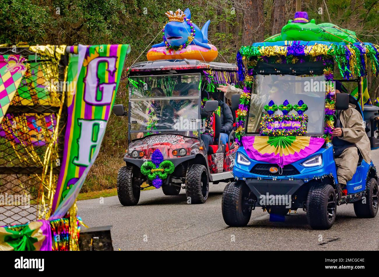 Les gens passent des voiturettes de golf décorées dans le défilé de Krewe de la Dauphine Mardi gras, le 21 janvier 2023, à Dauphin Island, Alabama. Banque D'Images