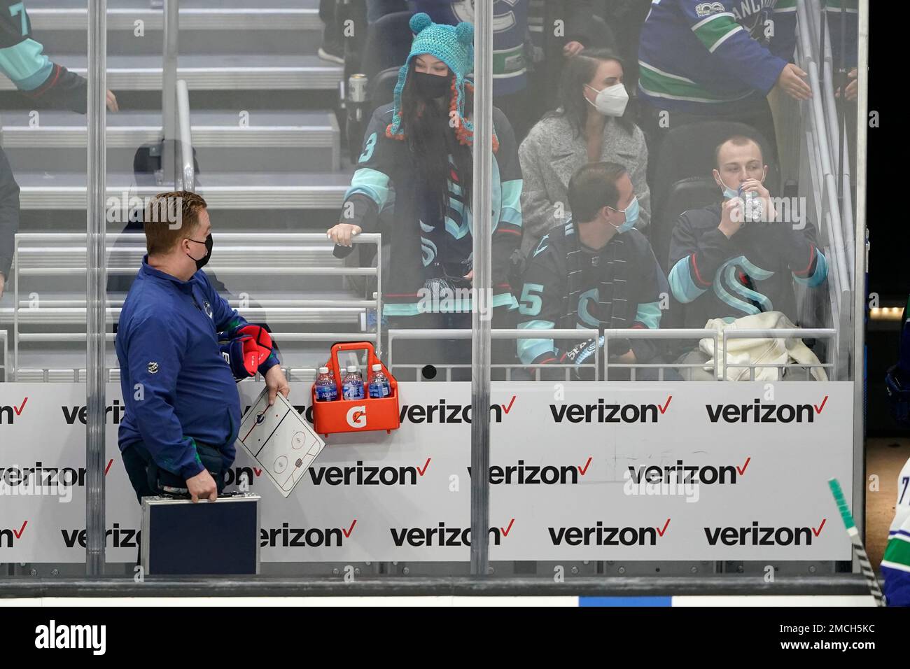 Seattle Kraken fan Nadia Popovici, center, looks toward Vancouver Canucks assistant equipment manager Brian "Red" Hamilton, left, at the end of an NHL hockey game, Saturday, Jan. 1, 2022, in Seattle. During a game between the two teams on Oct. 23, 2021, Popovici showed Hamilton a message on her phone expressing her concern that she believed a mole on the back of Hamilton's neck was cancerous and that he needed to get it checked. A few days later, doctors removed it and biopsy results showed there were cancerous cells in the mole. (AP Photo/Ted S. Warren) Banque D'Images