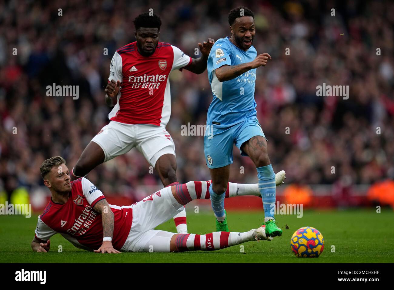 Arsenal's Ben White, down, and Arsenal's Thomas Partey challenge Manchester City's Raheem Sterling, right, during the Premier League soccer match between Arsenal and Manchester City at the Emirates Stadium, in London, England, Saturday Jan. 1, 2022. (AP Photo/Matt Dunham) Banque D'Images