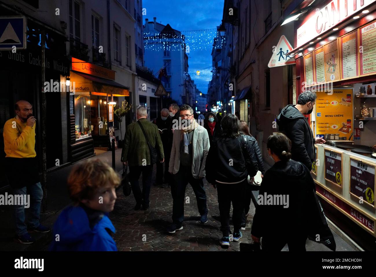 Pedestrians, some wearing protective face masks to prevent the spread of the COVID-19, walk in street market, in Paris, France, Friday, Dec. 31, 2021. Paris region health authorities have instructed hospitals to cancel more non-urgent medical procedures to free up intensive-care beds for the growing influx of people gravely sick with COVID-19. (AP Photo/Thibault Camus) Banque D'Images