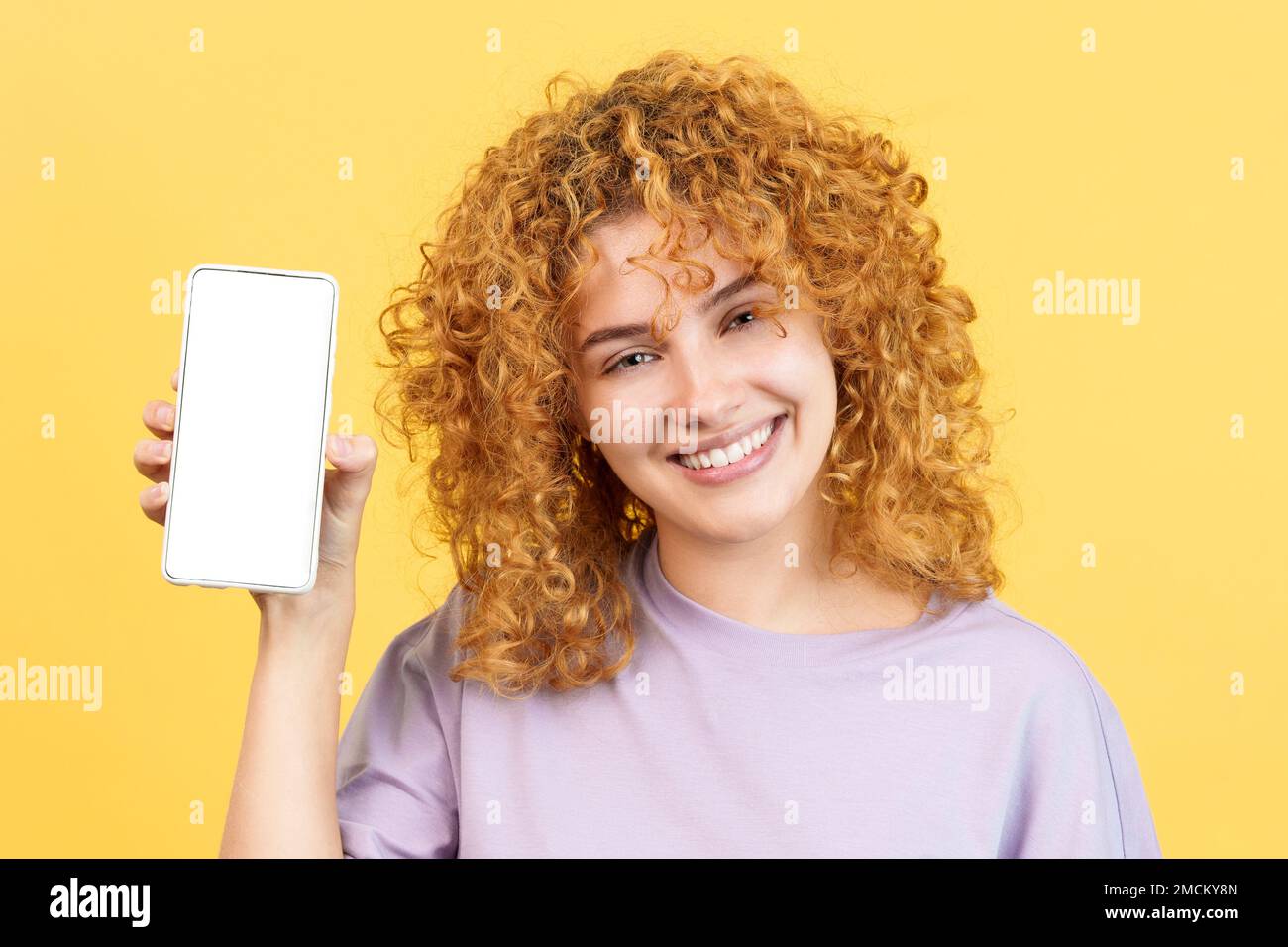 Femme souriante tenant un mobile avec un écran vide Banque D'Images