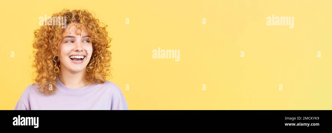 Femme souriante avec des cheveux bouclés regardant de côté Banque D'Images