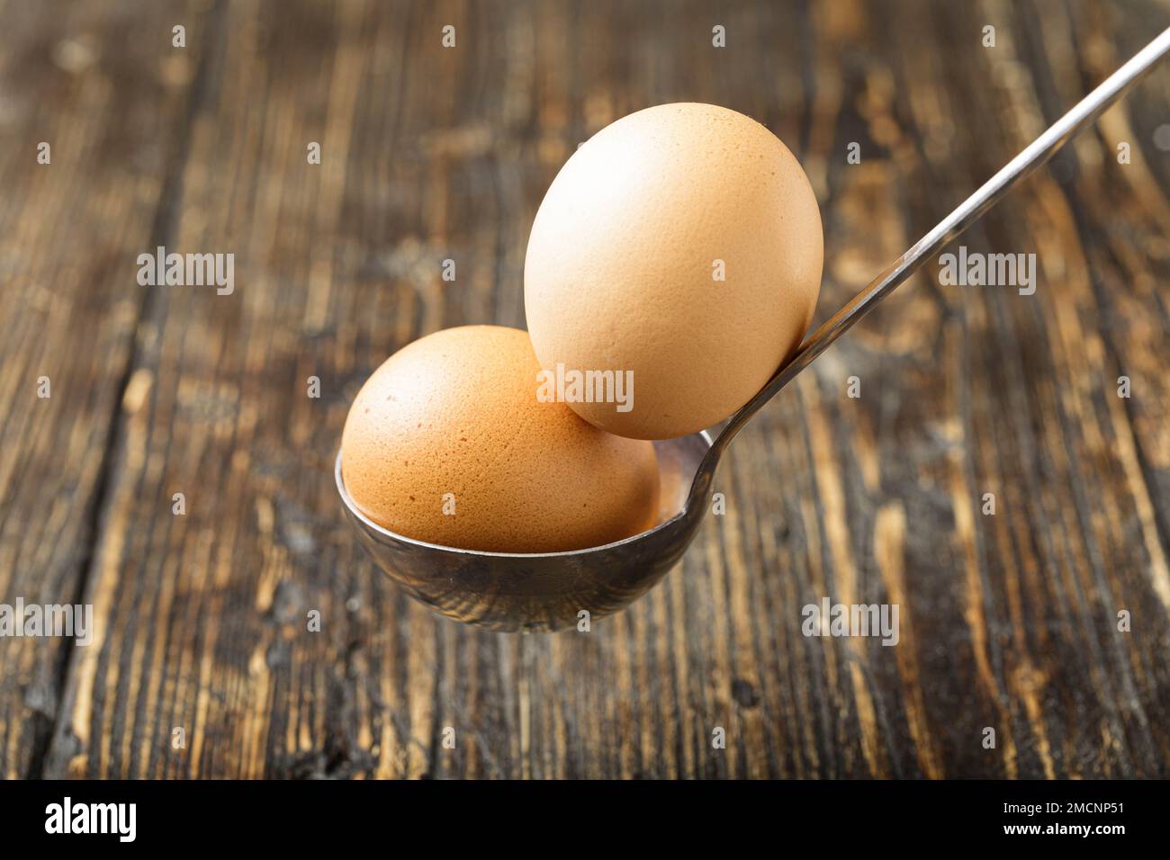 Deux oeufs bruns frais dans une louche de métal. Scène de cuisine rustique, ingrédients de cuisine. Banque D'Images
