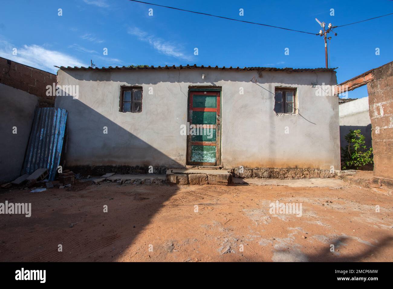 Une maison suburbaine africaine typique à Soweto avec des murs en béton et un toit en tôle de zinc, montrant des signes d'usure par les conditions météorologiques et le manque de résilience Banque D'Images
