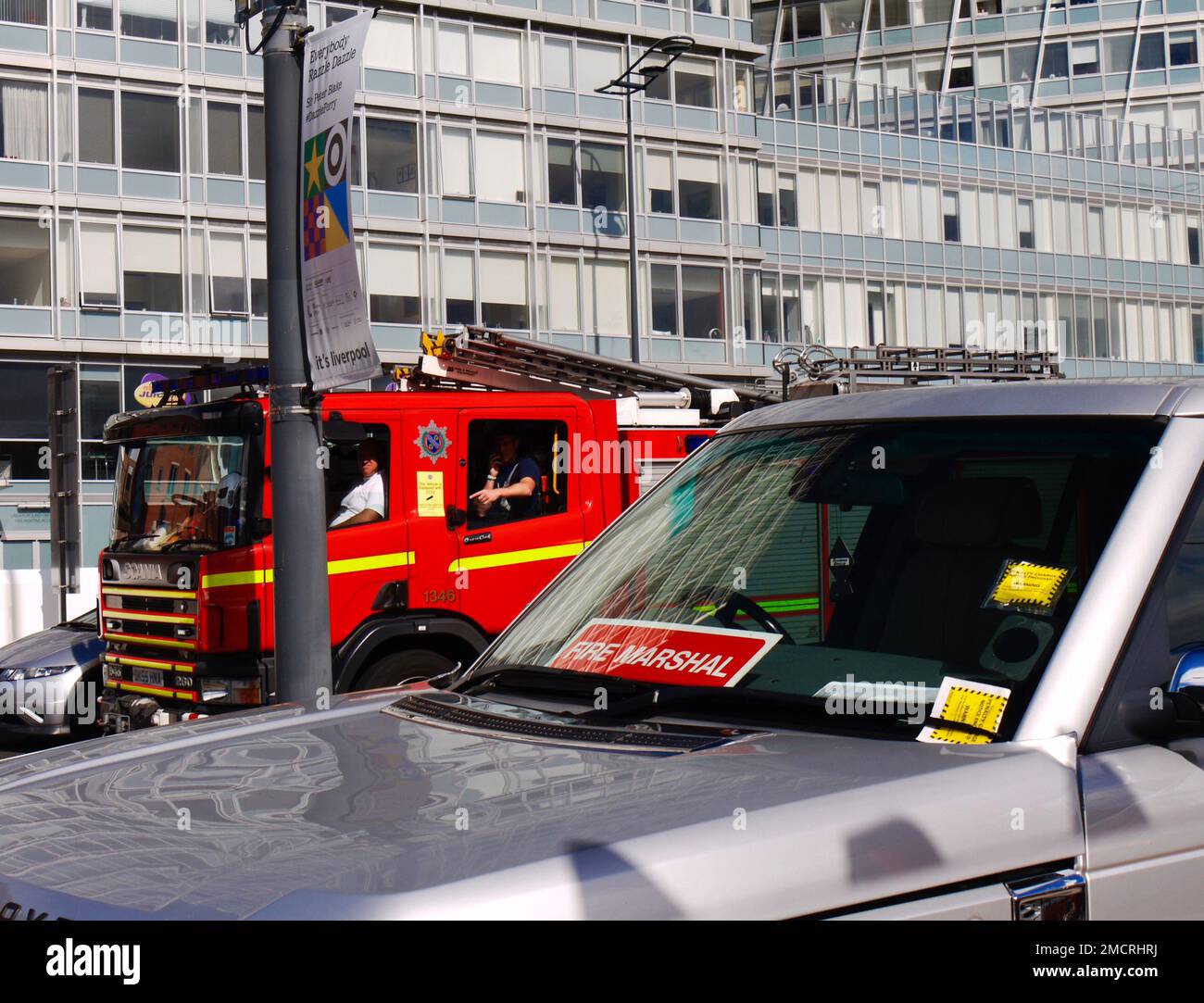 Pompiers dans un regard de machine d'incendie de passage, comme un véhicule appartenant à un Marshall d'incendie a reçu deux billets de stationnement. Liverpool, Royaume-Uni Banque D'Images